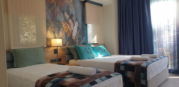 Habitación de hotel con dos camas, un ventanal con persianas y vistas al exterior.