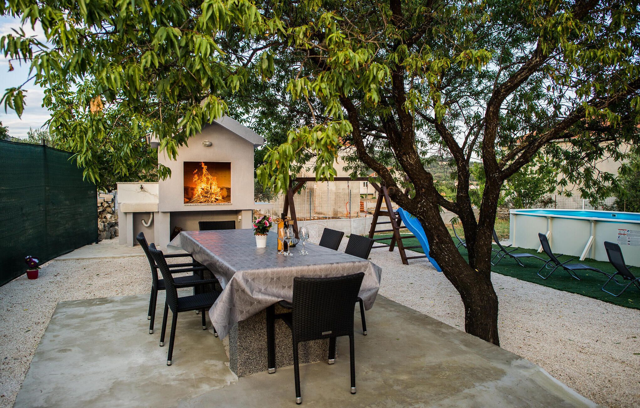 Un patio al aire libre con una parrilla, una mesa de comedor y sillas.