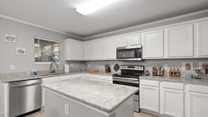 A modern kitchen with white cabinetry, granite countertops, stainless steel appliances, and a built-in island. - Epic Fun Luxury 4 BR in DFW w/ Casino & Lounge! (Grand Prairie)