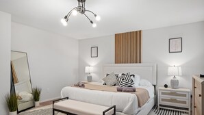 A modern bedroom with a large bed, bedside tables, a bench, and a mirror. - Epic Fun Luxury 4 BR in DFW w/ Casino & Lounge! (Grand Prairie)