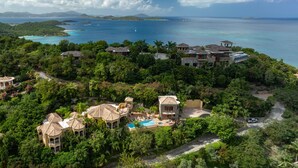 Una vista aerea di un resort con numerosi edifici immersi nel verde, una piscina e vista sull'oceano.