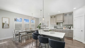 A modern kitchen with a central island, bar stools, and pendant lighting. - Family Oasis Getaway (Lehi)