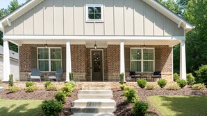 Une maison à deux étages avec un porche couvert, une façade en briques et une porte d’entrée.