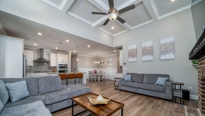 Un salon spacieux avec un canapé gris, une table basse en bois et un ventilateur de plafond.