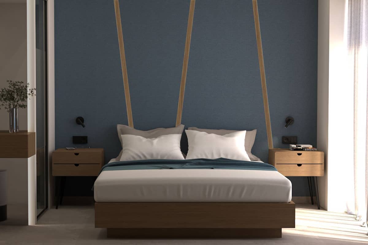 A modern bedroom with a large bed, bedside tables, a nightstand, a vase with a plant, and a window with curtains.