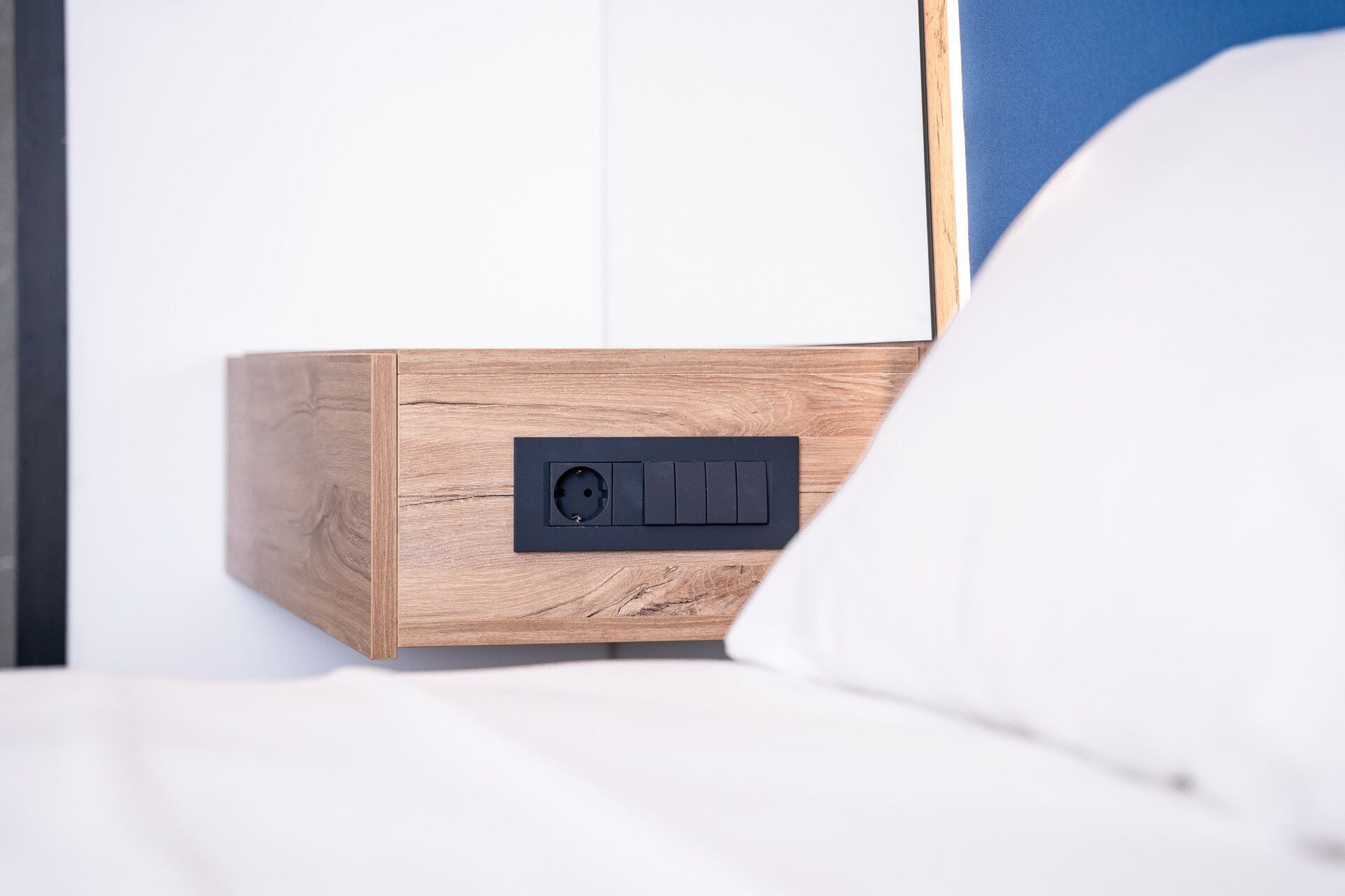 Un comodino in legno con una presa di corrente nera e un interruttore.