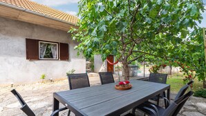 An outdoor patio with a table and chairs, a tree, and a building with a tiled roof. - Gorgeous home in Pridraga with WiFi (Pridraga)