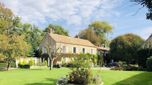 Une maison en pierre avec une pelouse et un jardin bien entretenus.