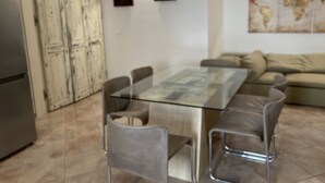 A modern living room with a glass-top dining table, grey chairs, a beige sofa, and a world map on the wall. - Entire apartment in the heart of Tuscany, between Val di Chiana and Val d'Orcia. (Sinalunga)