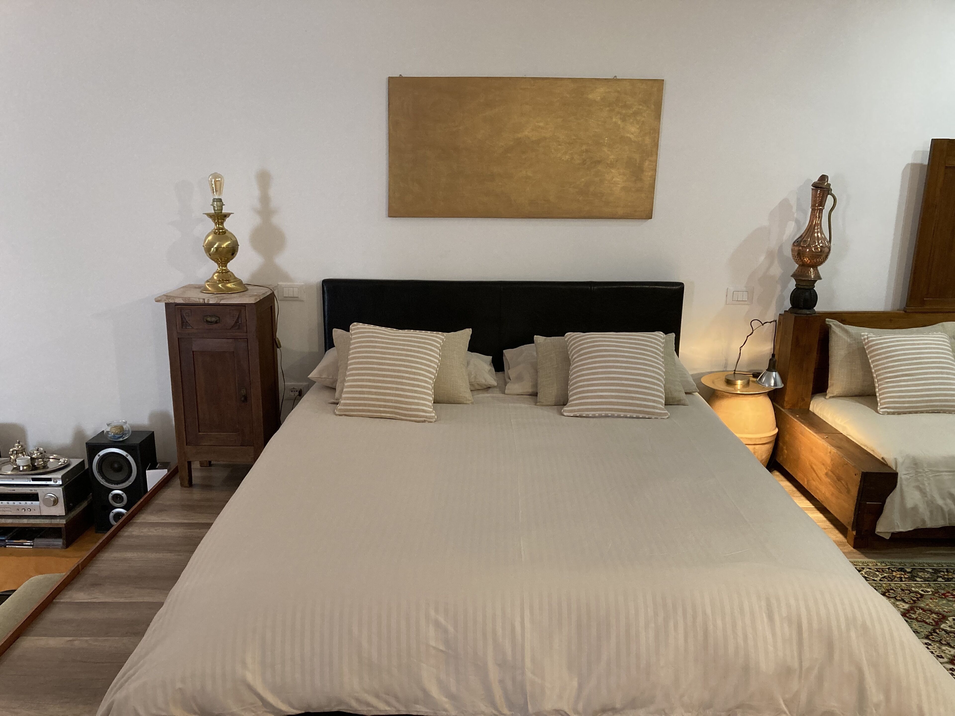 Een keurig opgemaakt slaapkamer met een groot bed, nachtkastjes, een houten kast en een radio.