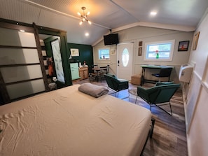 A bedroom with a bed, a desk, and a chair. There is a window with a view of a house. - Downtown Cottage (St. Augustine)