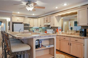 Una cocina moderna con una isla central, microondas, refrigerador y ventilador de techo.