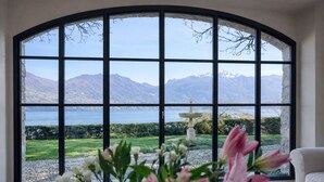 A room with a large arched window offering a view of mountains and a body of water. - Villa Gaia Luxury Retreat with Private Pool in Menaggio (Menaggio)