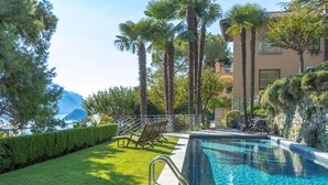 A swimming pool with a clear view of the sea, surrounded by palm trees and a well-maintained lawn. - Villa Gaia Luxury Retreat with Private Pool in Menaggio (Menaggio)