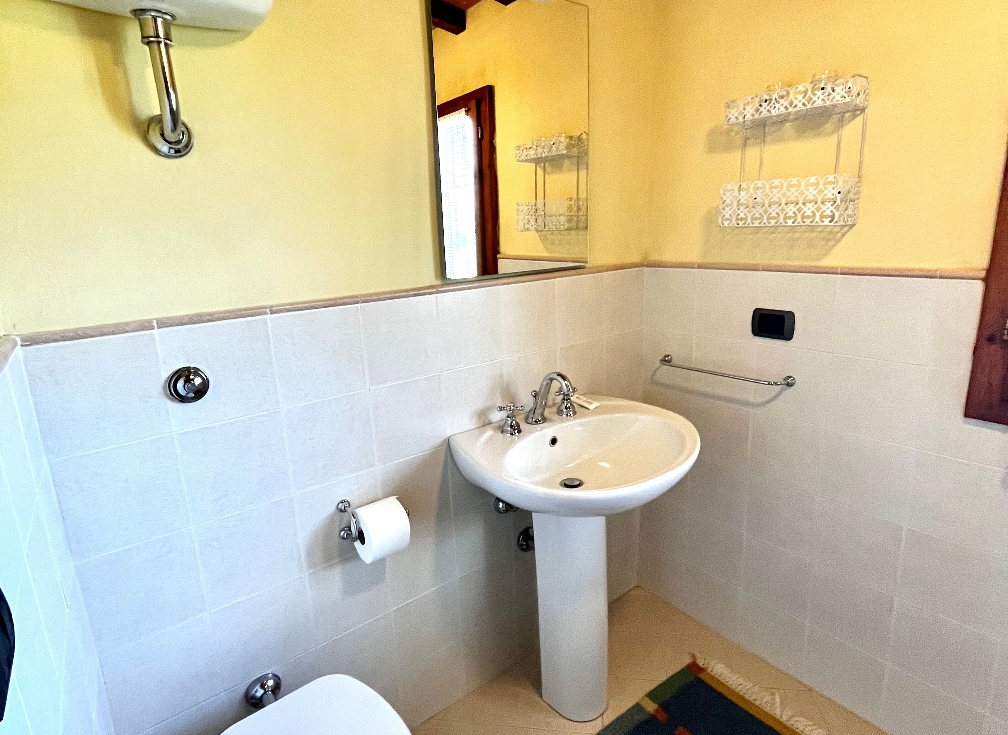 A bathroom with a pedestal sink, toilet, and a towel rack.