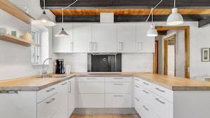 A modern kitchen with white cabinets, wooden countertops, and pendant lighting. - 3 bedroom cozy home in Bindslev (Bindslev)