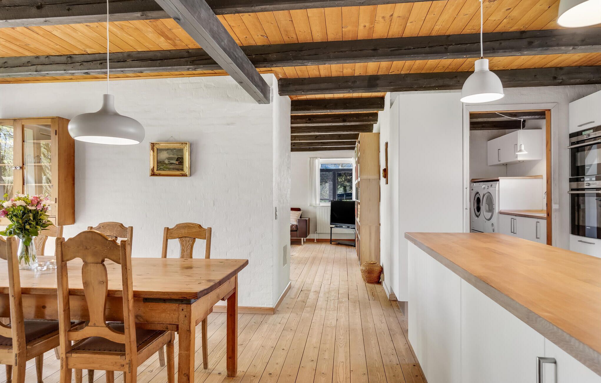Une cuisine moderne avec des armoires blanches, un plan de travail en bois et un four encastré.