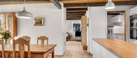 Une cuisine moderne avec des armoires blanches, un plan de travail en bois et un four encastré.