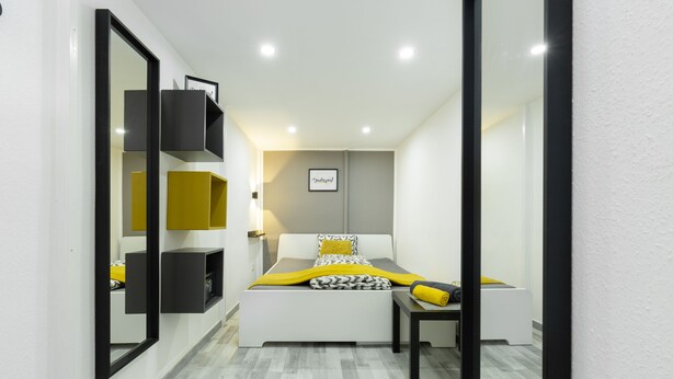 Un dormitorio moderno con cama, mesita de noche y estanterías empotradas.