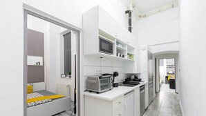 Una cocina compacta con gabinetes blancos, microondas, tostadora y pileta.