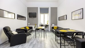 Una habitación de hotel moderna con sofá, sillas, una mesa de comedor y televisión.