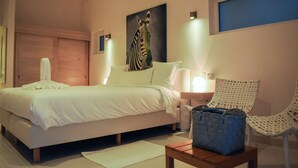 Un dormitorio con una cama, un cuadro de cebra, una silla y una mesita de noche.
