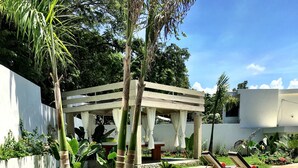 A well-maintained garden with a stone pathway, a pergola with white curtains, and lounge chairs. - Guest Friendly- 20% off for Bookings in 2024 (Sosua)
