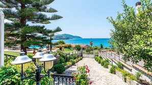 A stone pathway leading to a pool area with a view of the sea.