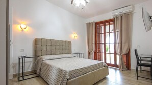 A bedroom with a large bed, a desk, and a chair.