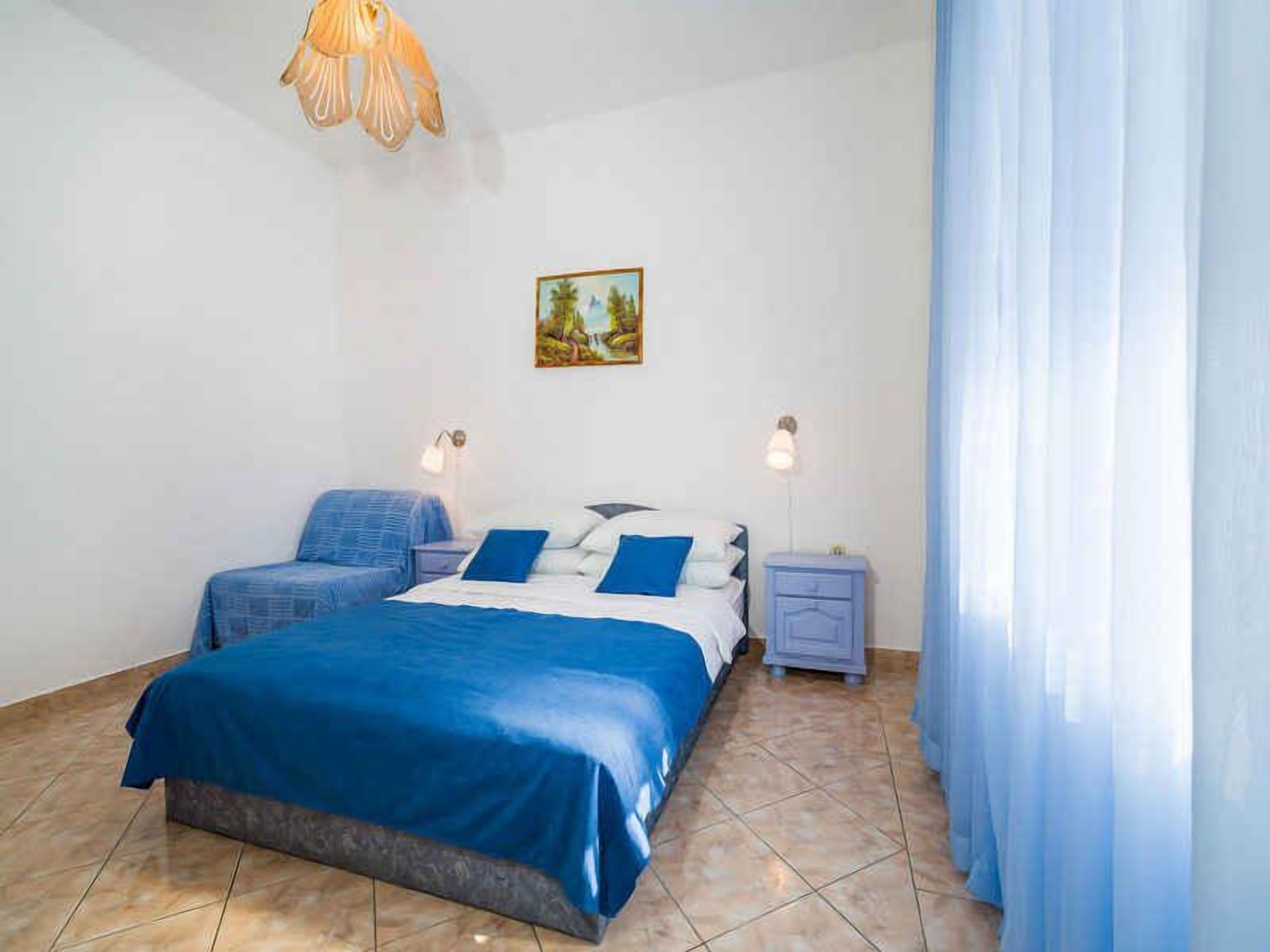 Une chambre avec deux lits, un tableau au mur et un lustre.