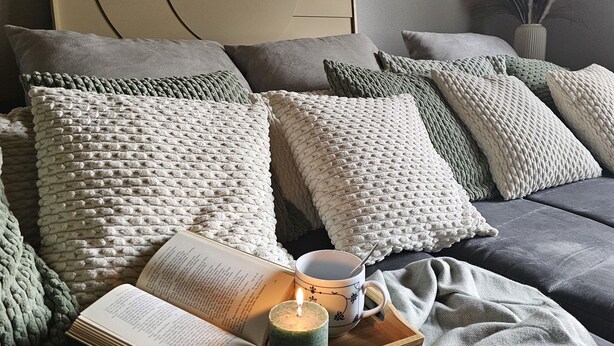 A neatly arranged bedroom with a bed, pillows, a bedside table with a book and a mug, and a wall art piece. - Modernes Wohnenauf dem Land (Langsur)