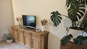 A wooden cabinet with a flat-screen TV, a potted plant, and decorative items on top. - Modernes Wohnenauf dem Land (Langsur)