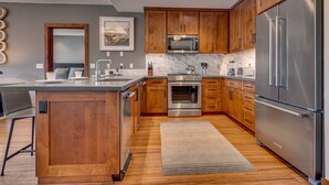 A modern kitchen with wooden cabinets, stainless steel appliances, a marble countertop, and a central island. - Resort! Walk to Skiing/ Casinos/ Beach, Pool & Spa, Gym, Grill: Zalanta Oasis (South Lake Tahoe)