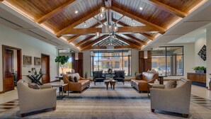 A spacious lobby with wooden beams, leather sofas, and a large window offering a view of the building. - Resort! Walk to Skiing/ Casinos/ Beach, Pool & Spa, Gym, Grill: Zalanta Oasis (South Lake Tahoe)