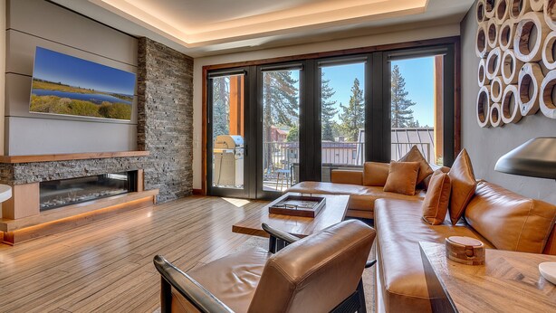 A modern living room with a fireplace, leather sofa, and a large TV mounted on the wall. - Resort! Walk to Skiing/ Casinos/ Beach, Pool & Spa, Gym, Grill: Zalanta Oasis (South Lake Tahoe)