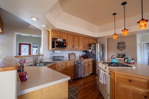Enjoy cooking in this well-equipped kitchen with a central island, sink, dishwasher, gas stove, microwave, and refrigerator.