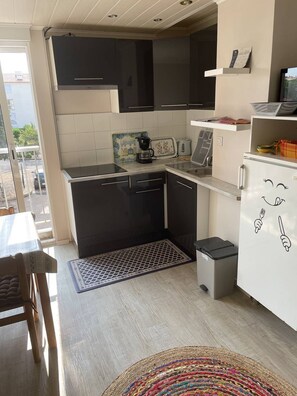 Een koelkast, een microgolfoven, kookgerei, borden en bestek