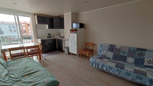 Ett kompakt bostadsutrymme med ett litet kök, en soffa, ett matbord med stolar och en liten TV.