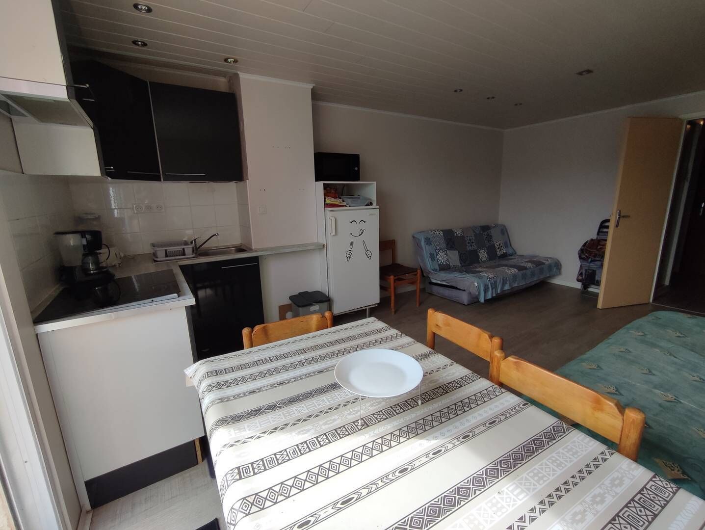 Un espacio habitable compacto con kitchenette, una mesa de comedor con un plato, un sofá y una cama.