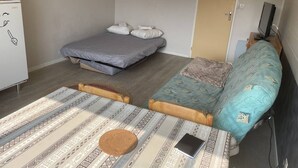 Ett litet rum med en säng, en soffa, ett litet bord och en tv.