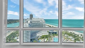 A hotel with multiple floors, a pool, and a view of the ocean and cityscape.