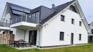A modern two-story house with a balcony, solar panels, and a well-maintained lawn. - Schwedengang 7A Whg.1 Unten Links (Zingst)