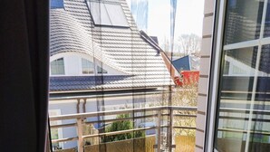 Ein Balkon mit Blick auf benachbarte Häuser und einen klaren Himmel.
