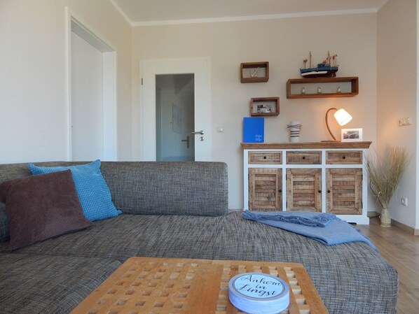 Un salon avec un canapé gris, une table basse en bois et un meuble avec des tiroirs.