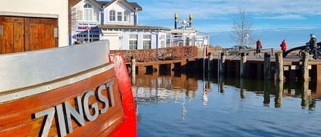 Un barco rojo llamado ZINGSI atracado en un muelle, con un edificio al fondo.