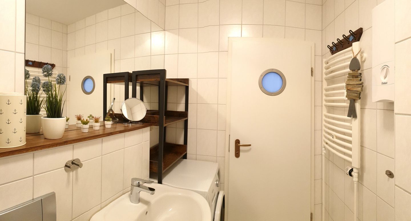 A bathroom with a sink, mirror, towel rack, and a door with a towel hanging on it.