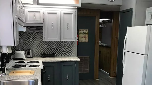 Una cocina con armarios blancos, microondas, tostadora y refrigerador.