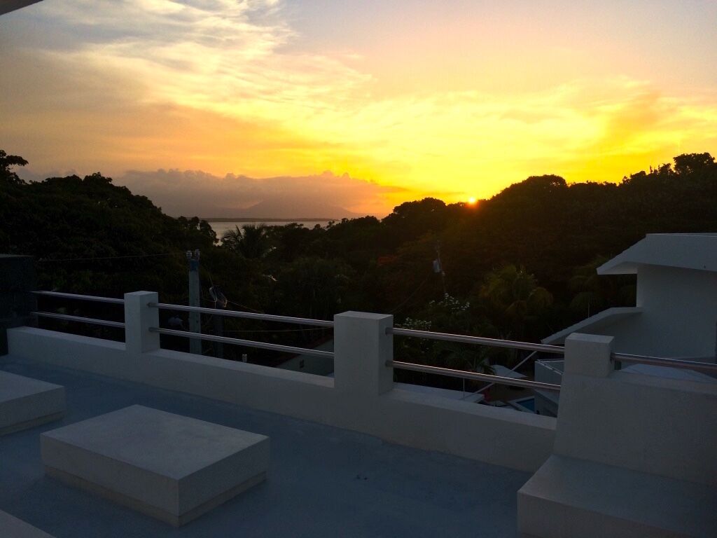 A sunset view from a balcony with a railing and a few steps leading down.