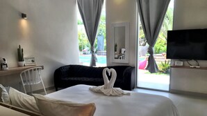 A hotel room with a bed, a TV, a desk with a lamp, and a window with curtains.