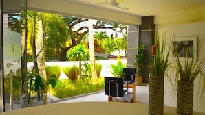 A modern room with a large window, a ceiling fan, and a view of tropical greenery outside.
